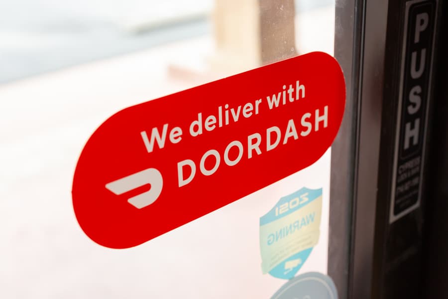 A View Of A Window Sticker That Advertises A Local Restaurant Provides Food Delivery Through Doordash.