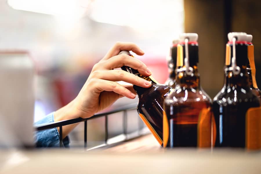 Hand Taking Bottle Of Beer From Shelf In Alcohol And Liquor Store