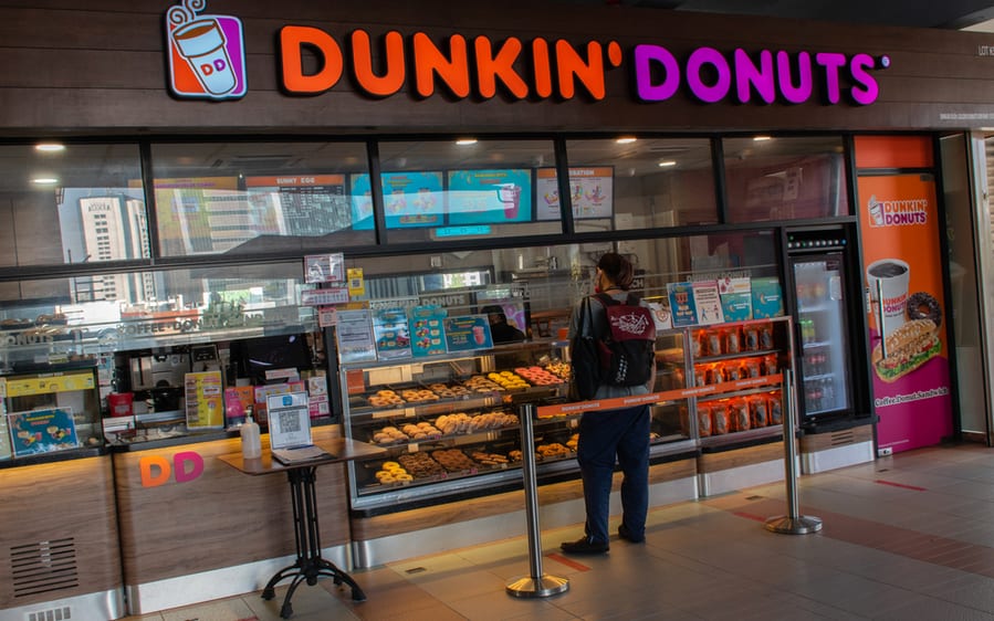 A Counter Staff Attending To Customer Purchase In Dunkin' Donuts Store