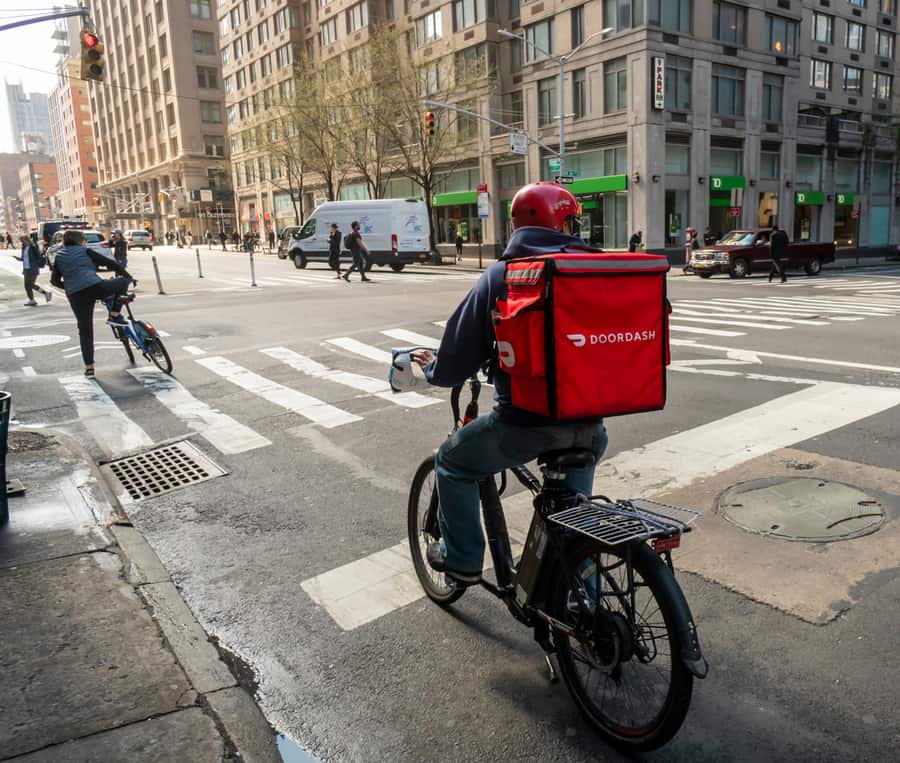 A Delivery Person With A Doordash Branded Tote On His Bicycle