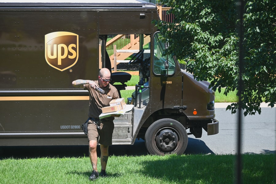 An Ups Delivery Driver Scans A Package Before Leaving The Order At A House.