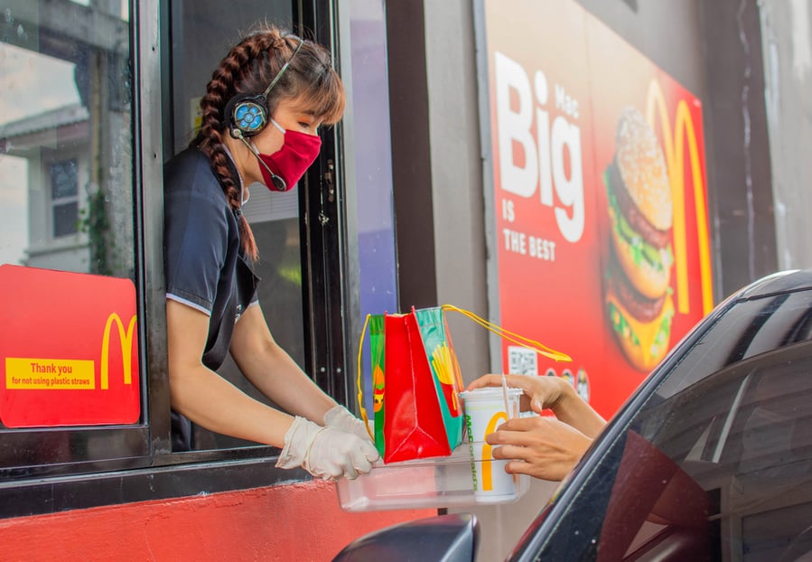 Female Staff At Mcdonald's Deliver Food To Customers Through The Door Of The Car At The Pick Up.