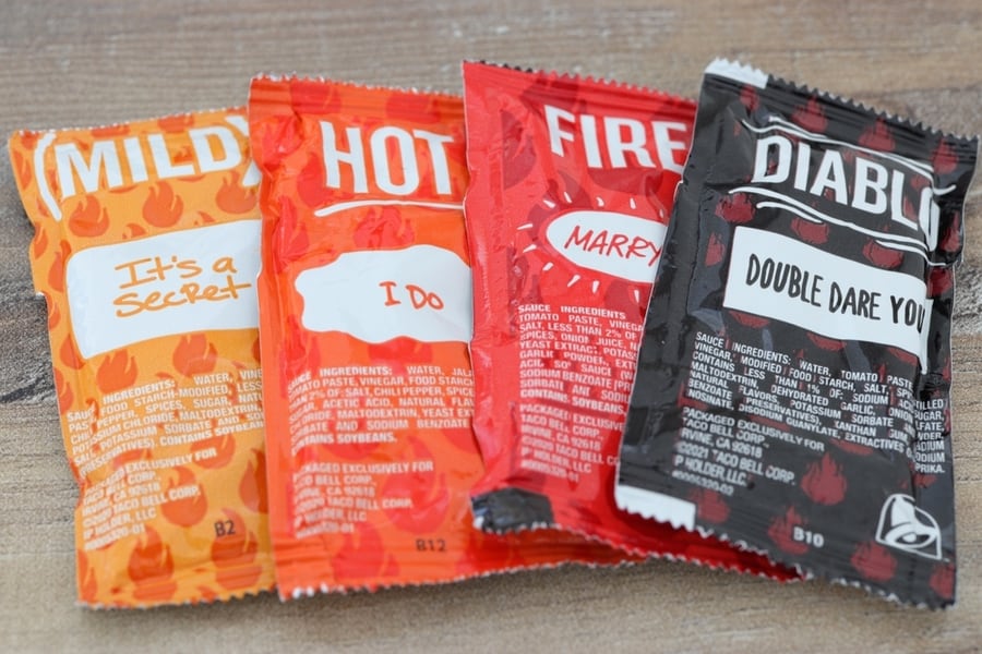 Four Isolated Packets Of Taco Bell Condiments.