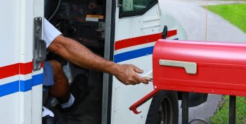 Mail Man Reaches Out Of His Truck To Deliver Mail.