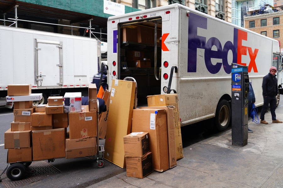 View Of A Pile Of Packages By A Fedex Delivery Truck Parked On The Street