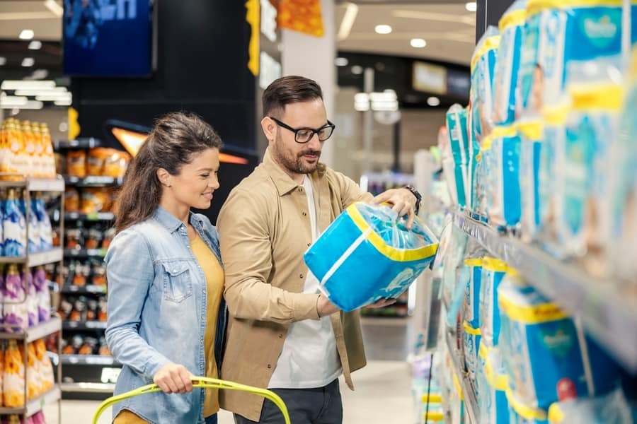 A Happy Couple Is Buying Diapers For Their Baby In Supermarket