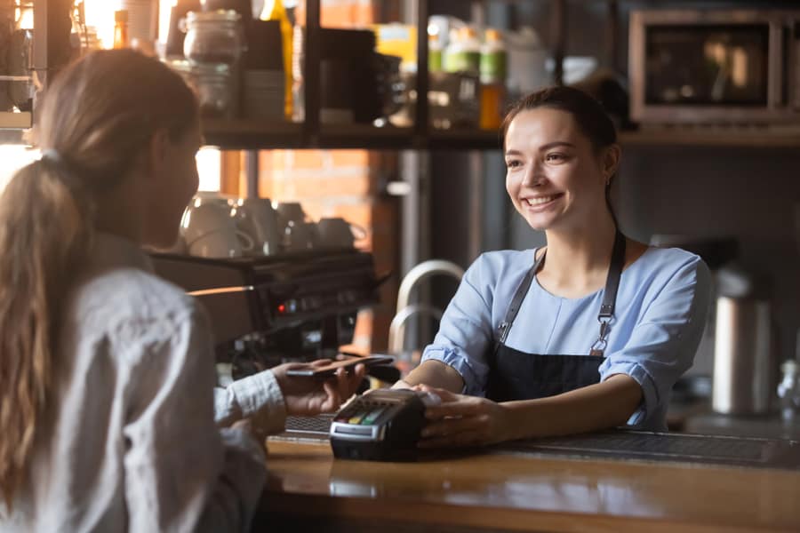 Female Customer Holding Phone Make Contactless Mobile Payment With Smiling