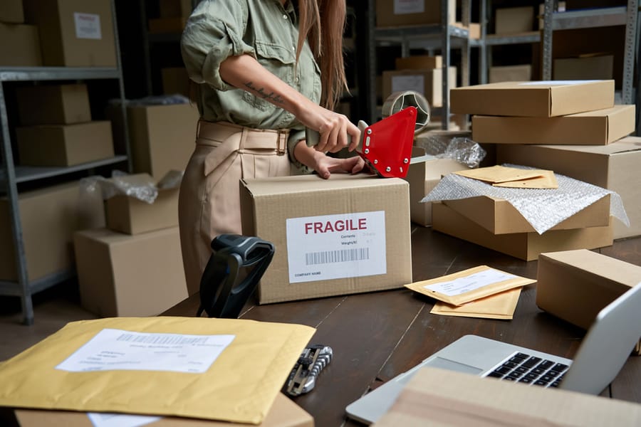 Female Post Mail Storage Worker Holding Tape Dispenser Sealing