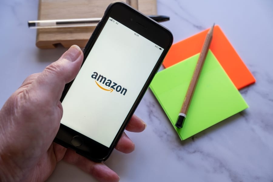 Man Holding A Smart Phone With Amazon Logo