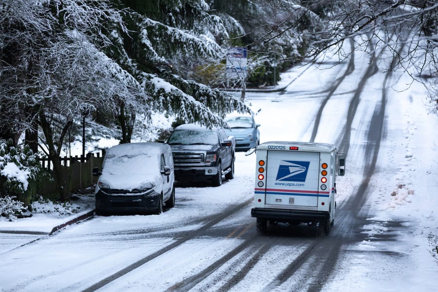 United States Postal Service (Usps) Delivery Truck Driving Down A Snowy Residential Street