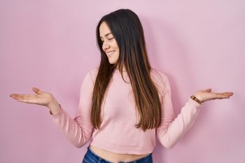 Young Brunette Woman Standing Over Pink Background Smiling Showing Both Hands Open Palms